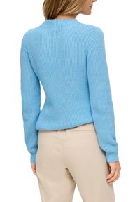Hellblauer gestrickter Pullover mit rundem Halsausschnitt, langen Ärmeln und einem strukturierten Muster, kombiniert mit beigen Hosen.