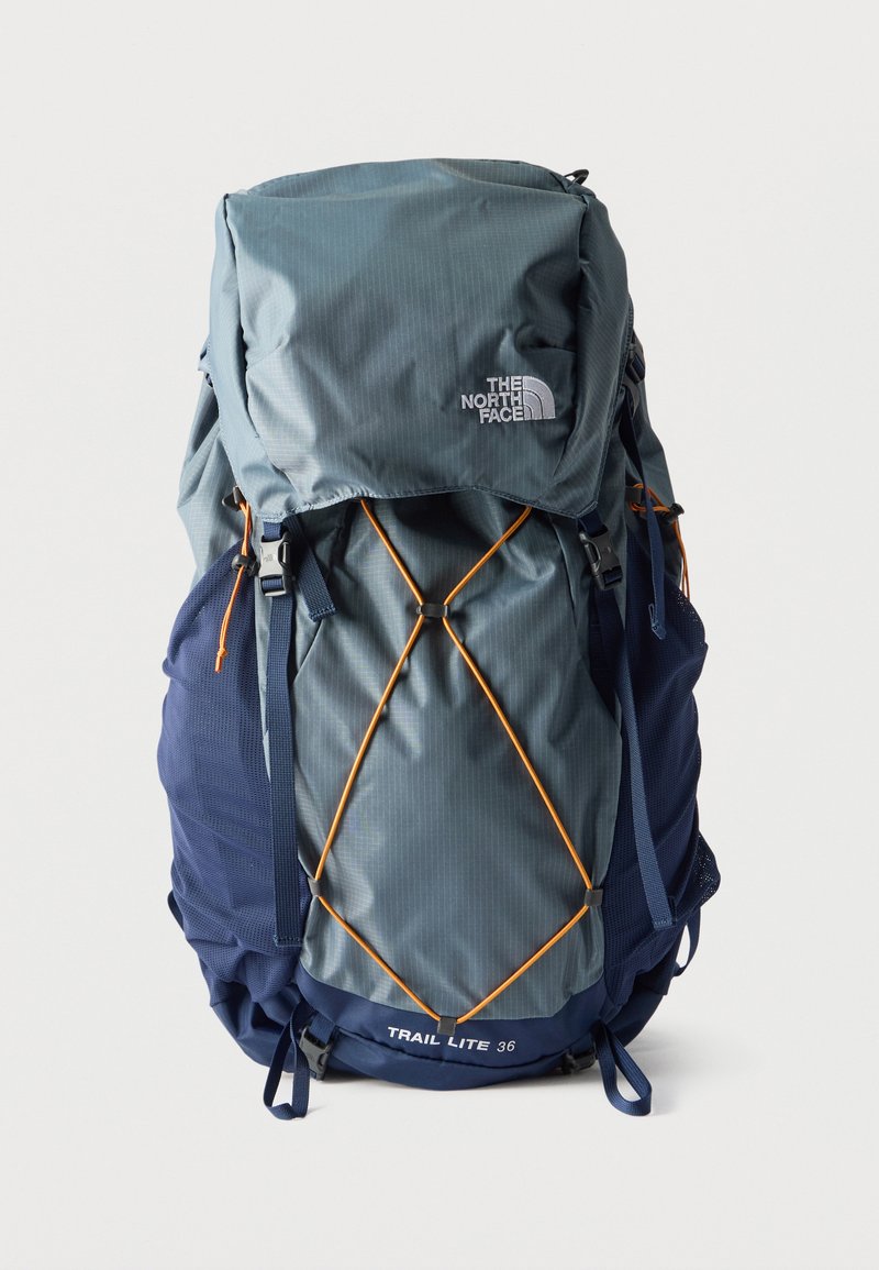 Γκρι και ναυτικό μπλε σακίδιο πεζοπορίας The North Face Trail Lite 36 με πορτοκαλί ελαστικό κορδόνι στο μπροστινό μέρος και πολλαπλούς ιμάντες.