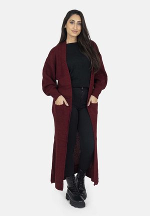 Burgundy long cardigan with a textured knit design, open front, and side pockets, paired with black top and pants, and black combat boots.