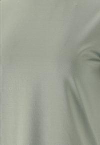 Ljust grönt kortärmat t-shirt gjort av mjukt, stretchigt tyg med en slät textur och en enkel, omönstrad design.