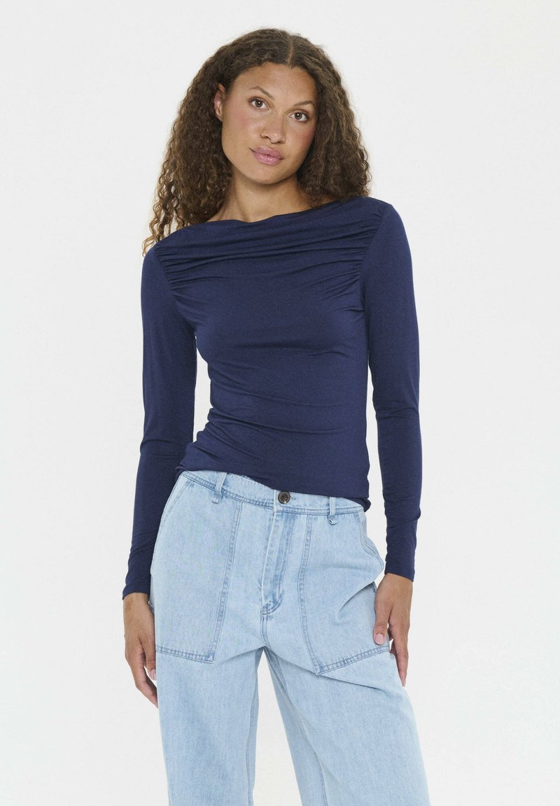 Camiseta de manga larga de color navy con escote drapeado y cuerpo ajustado. Confeccionada en tejido elástico, presenta una sutil textura y mangas largas.
