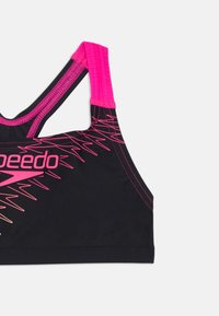 Top de natação preto com detalhes em rosa e linhas em zigue-zague, com um design de alças nadadoras e tiras elásticas para suporte. Textura de tecido suave.