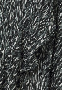 Tissu imprimé avec un motif abstrait noir, gris et blanc ; présente une texture douce et un design fluide avec des bords froncés.