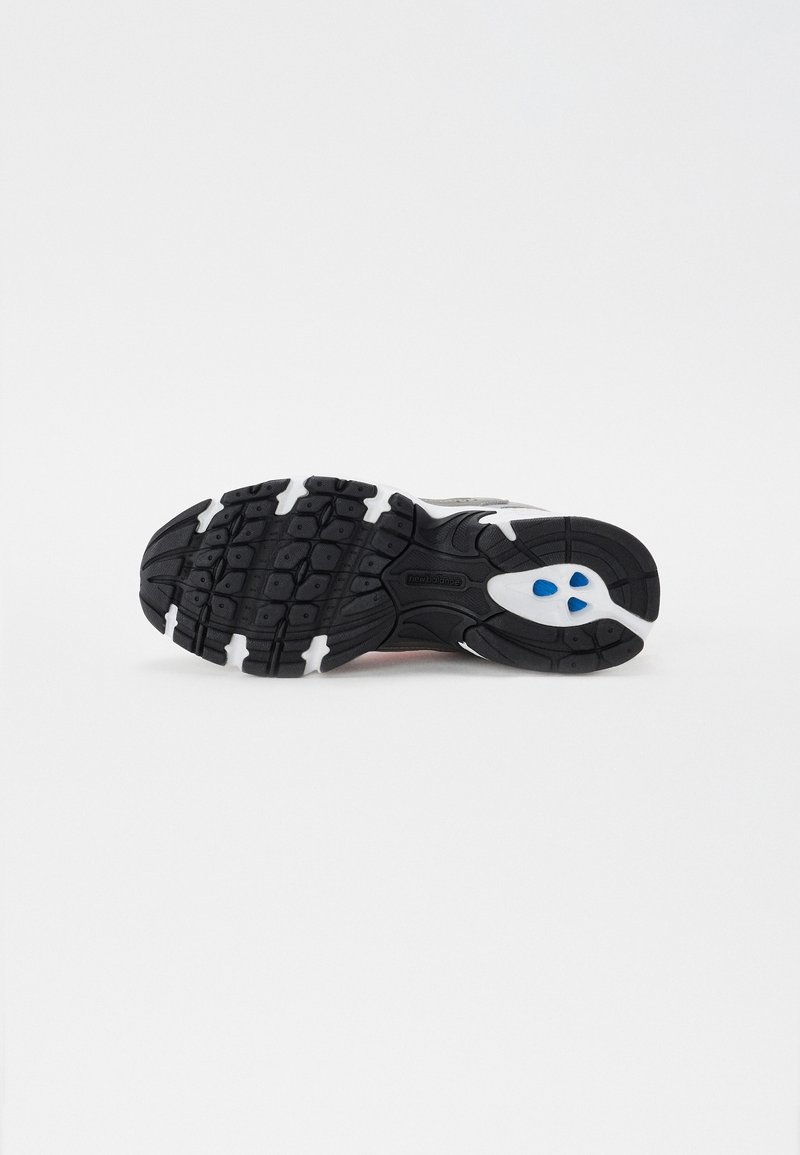 Schwarz-weiße Sohle eines Sportschuhs aus strukturiertem Gummi mit gutem Grip, versehen mit blauen Akzenten und einem Logo sowie einem geschwungenen Design für Flexibilität.