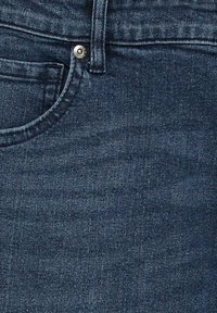 Jeans de mezclilla en azul oscuro con un acabado texturizado, que cuentan con un diseño clásico de cinco bolsillos y un cierre de botón metálico en la cintura.