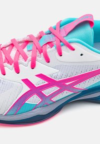 Basket blanc avec des accents roses et des détails turquoise. Tige en mesh et semelle de soutien avec un branding bien visible sur le côté.