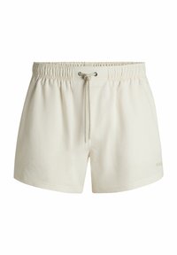 Cream-colored swim shorts with a textured fabric, elastic waistband, and drawstring. Features a subtle brand logo on the lower right.
