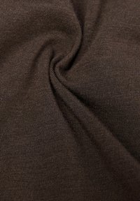 Brunt stretchtyg med en slät textur, som har ett fint ribbat mönster, sömlöst vridet i en cirkelform.