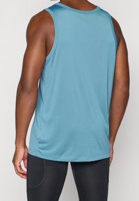 Męski bezrękawnik w kolorze niebieskim, wykonany z lekkiego materiału. Posiada okrągły dekolt oraz luźny krój z delikatnymi bocznymi szczelinami.