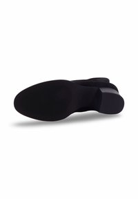 Bottine noire à la semelle en caoutchouc texturé, à bout rond et en matière supérieure lisse. Détails de couture subtils le long de la couture.
