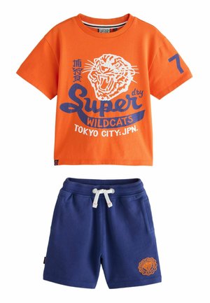Oranje katoenen t-shirt met een witte tijgerafbeelding en blauwe tekst, gecombineerd met marineblauwe shorts met een geborduurd oranje tijgerlogo en een trekkoord.