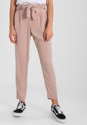 Lichtroze tailored broek met een strik taille, voorzien van plooien en een recht model, gecombineerd met zwart-witte sneakers.