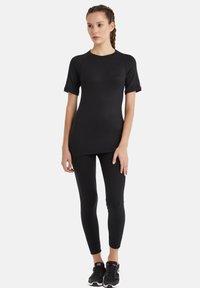 Svart träningsoutfit bestående av en kortärmad topp och leggings, tillverkad av stretchigt tyg med en slät textur och en åtsittande design.