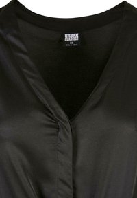 Blouse noire en tissu soyeux avec col en V et détail froncé près de l'encolure, étiquette Urban Classics, taille XS, fabriquée en Chine.