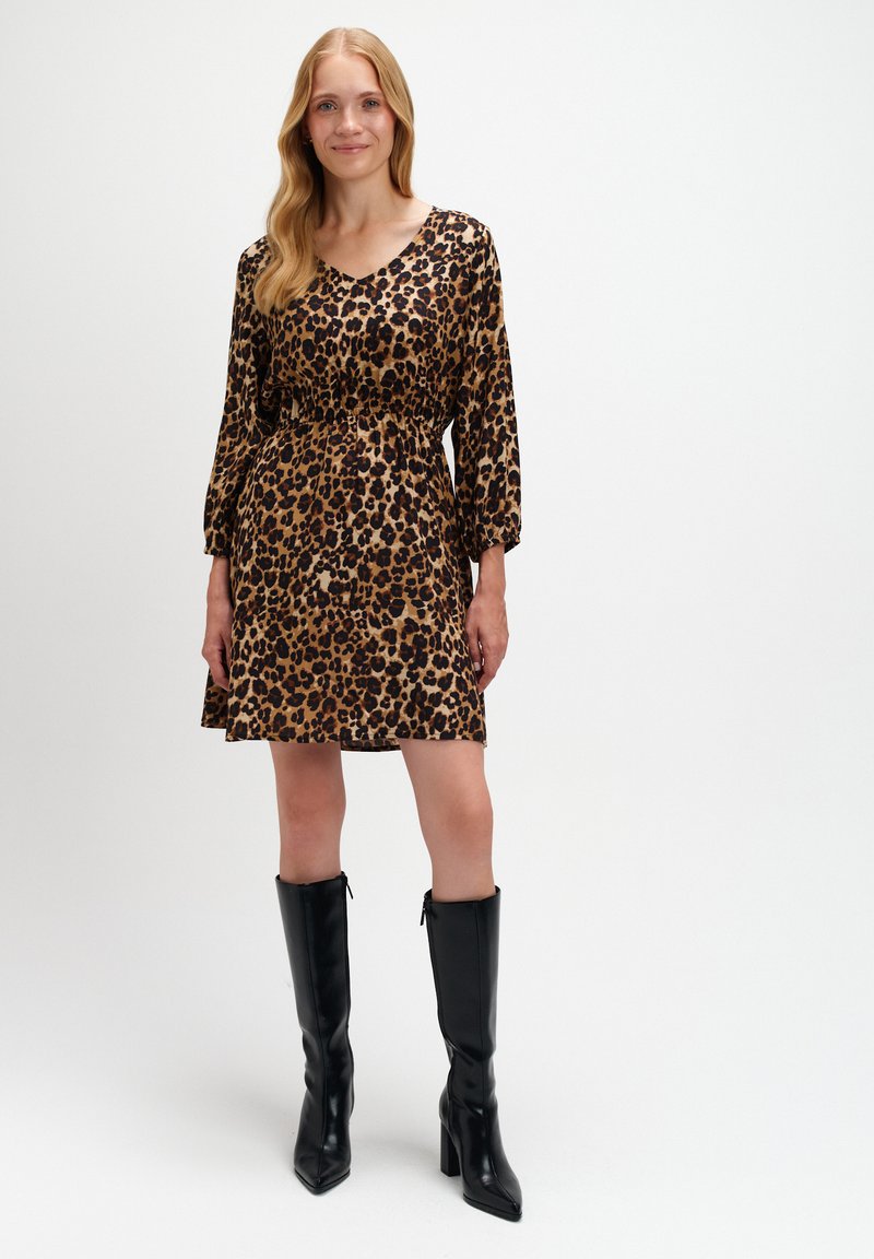 Sukienka w panterkę z dekoltem w serek, długimi rękawami, elastyczną talią i zwiewnym dołem. W komplecie z długimi czarnymi skórzanymi botkami.