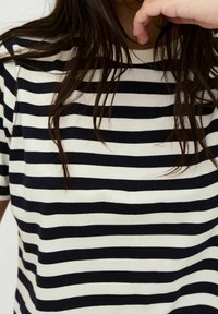 Svart och vit randig t-shirt med rund halsringning, korta ärmar och avslappnad passform, tillverkad av ett mjukt, slätt tyg.