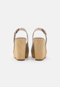 Sandali con zeppa beige caratterizzati da un tacco in paglia testurizzata, una cinturino alla caviglia regolabile e una parte superiore in materiale liscio. Tra gli accessori spicca una fibbia in metallo.