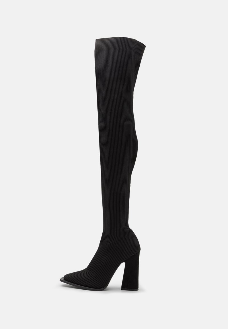 Zwarte over-de-knie laarzen gemaakt van ribbelstof, met een puntige neus en een stevige hoge hak voor stabiliteit.