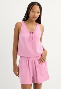 Top sin mangas rosa con parte delantera con cordones y corte holgado, combinado con pantalones cortos rosa a juego con cinturilla elástica y bolsillos laterales.