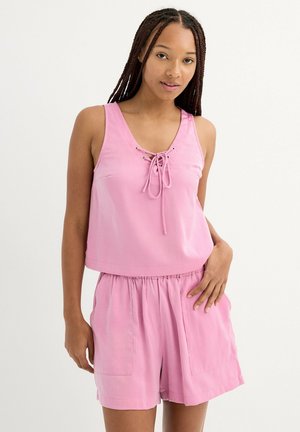 Top sin mangas rosa con parte delantera con cordones y corte holgado, combinado con pantalones cortos rosa a juego con cinturilla elástica y bolsillos laterales.