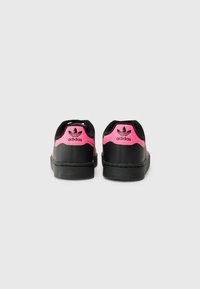 Sorte lærersneakers med rosa detaljer på hælen og logo, med en glat overflade og rund tådesign.