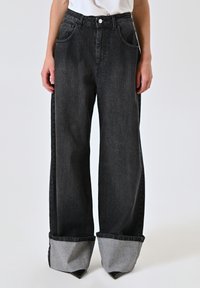 Zwarte wijde jeans met hoge taille, voorzien van grote zijzakken en omgeslagen grijze denim manchetten. Gemaakt van stevig katoen.