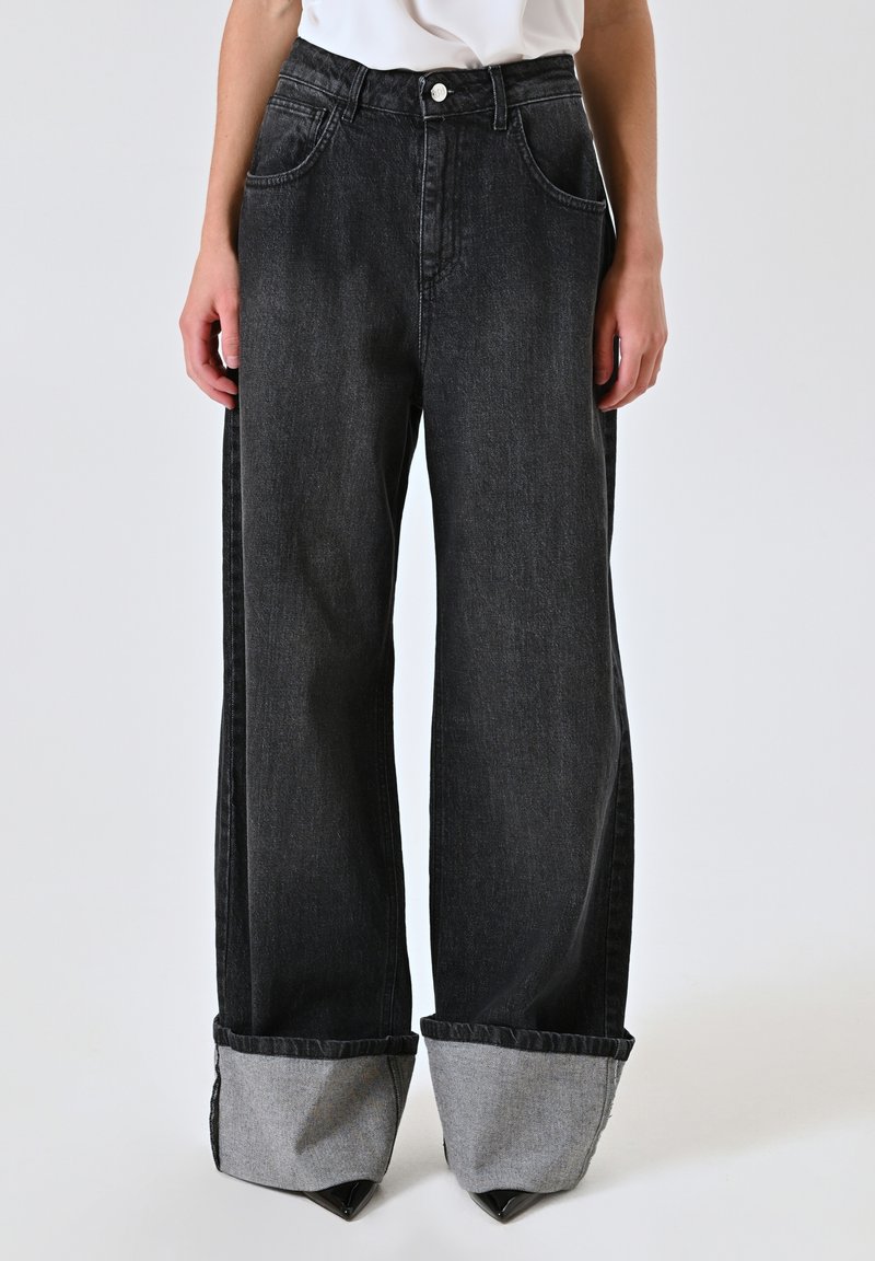 Zwarte wijde jeans met hoge taille, voorzien van grote zijzakken en omgeslagen grijze denim manchetten. Gemaakt van stevig katoen.