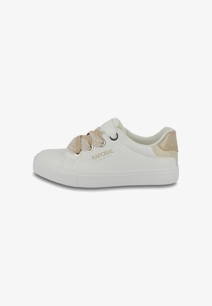 Zapatilla blanca con acentos beige y cordones con patrón, hecha de material sintético. Presenta un cuello acolchado y un logo sutil. Suela de goma plana.