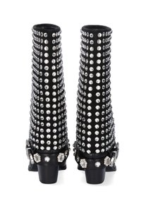 Botas negras con un diseño alto y estrecho, cubiertas de tachuelas plateadas, con una hebilla decorativa y acentos de perlas en las correas del tobillo.