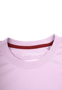 Ljuslila bomulls t-shirt med en röd inre halsringning. Har en rundad krage och en etikett som anger "Band of Rascals."
