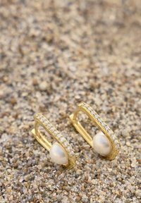 Pendientes de oro con un diseño curvado, que presentan una perla central y una fila de cristales transparentes a lo largo de un borde. Acabado en metal texturizado.