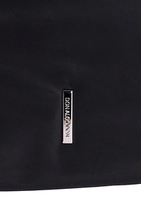 Tela negra lisa con una etiqueta rectangular vertical de metal plateado grabada con la palabra "DON ALGODON" en letras mayúsculas.