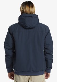 Marineblaue, leichte Jacke mit Kapuze, elastischen Bündchen und Saum. Glatte Textur mit einem klaren, minimalistischen Design und ohne sichtbare Markenkennzeichnung.