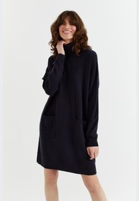 Abito lavorato a maglia navy con colletto alto, maniche lunghe e due tasche frontali. Forma a trapezio con polsini e orlo a coste. Texture morbida.
