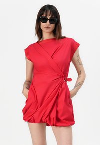 Rotes Wickelkleid mit kurzen Ärmeln, geknotetem Detail an der Taille und Taschen. Glatte Textur mit fließender Silhouette und gerafftem Rock.