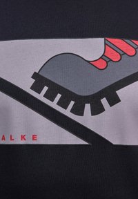 Grafische print t-shirt met een gestileerde grijze en rode schoen met zwarte zolen op een witte achtergrond, geplaatst op een donkere stof. De tekst zegt "ALKE."