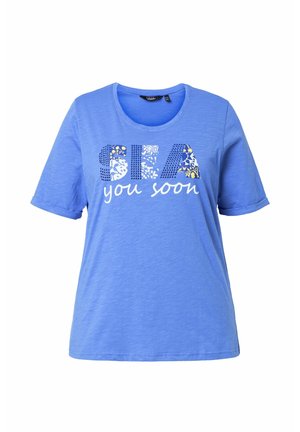 Blaues T-Shirt mit kurzen Ärmeln und rundem Ausschnitt, mit dem Schriftzug "SEA" in gemusterten Buchstaben und darunter "you soon" in weißer Schreibschrift.