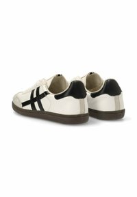 Zapatillas blancas con rayas negras, suela de goma texturizada, parte superior de cuero liso y acentos en negro contrastantes en el talón. Diseño deportivo clásico.