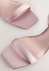 Sandali rosa in raso con tacco a blocco, design con punta quadrata, dotati di ampie fasce e superficie liscia. Semplici, eleganti e moderni.