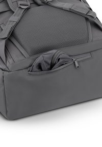 Mochila gris con un respaldo de malla texturizada y un bolsillo delantero con cremallera. Fabricada con tejido duradero, cuenta con correas ajustables para mayor comodidad.