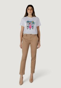 Witte katoenen T-shirt met een kleurrijk grafisch ontwerp, gecombineerd met beige slim-fit broek en beige hakken. Eenvoudige snit, geen patronen op de broek.