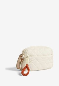 Borsa a tracolla bianca trapuntata con superficie texturizzata, caratterizzata da un tirazip rotondo arancione intrecciato e da una tracolla regolabile beige.
