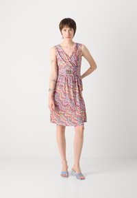 Robe avec un motif zigzag vibrant en rose, jaune et bleu. Dispose d'un décolleté en V, d'un cintrage à la taille et d'un tissu doux. Assortie à des talons bleu clair.