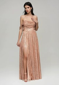 Roséguld, paljettklänning för kvällen med axelbandslös, draperad byst och en slits upp till låret. Flödande textur med glittrande detaljer.