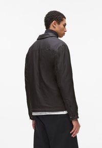 Must mustast jacket teraga kollane, nööbidel mansetid ja tekstureeritud kangas. Seljaosa on sujuva disainiga ja õrnalt läikiv.