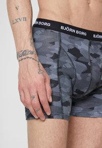 Fekete és szürke kamuflázs mintás boxer alsónadrág, fekete elasztikus derékpánttal,amelyen fehér "BJÖRN BORG" felirat található. Simább anyagtextúra.
