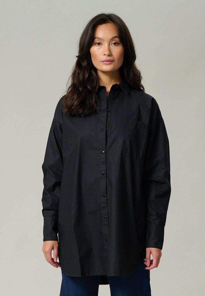 Sort langærmet skjorte lavet af let stof, med en knaplukning foran, en lomme og en afslappet pasform med en buet kant.