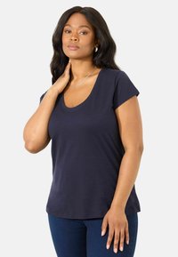 T-shirt blu navy a maniche corte con scollo a barca, realizzato in tessuto morbido. Presenta una vestibilità rilassata e una texture liscia e leggera.