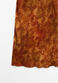 Tissu rustique en orange profond avec un motif floral et de feuilles texturé. Surface lisse avec un ourlet ondulé, montrant de riches détails tout au long.
