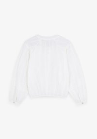 Blouse blanche à manches longues en tissu léger avec des rayures verticales, ourlet élastiqué et poignets à boutons. Détails de texture subtile partout.
